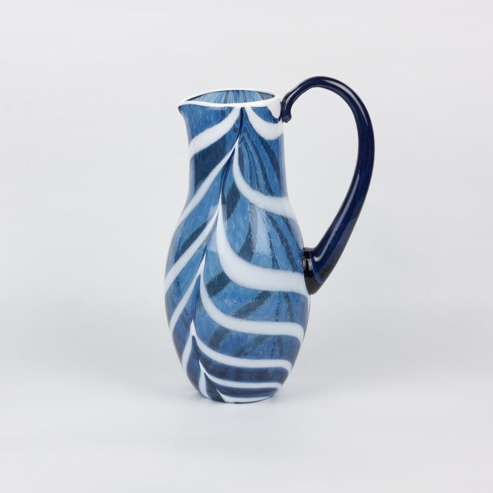 Blue and white ceramic pitcher on a light gray background