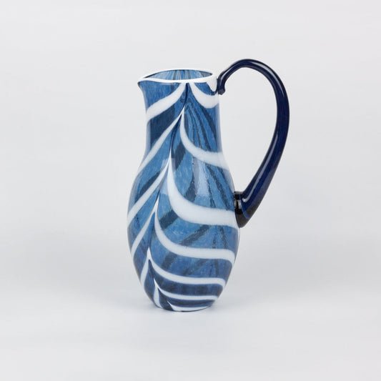 Blue and white ceramic pitcher on a light gray background